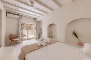 a white bedroom with a large bed and a window at White Suites in Ermoupoli