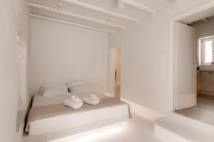 a white bedroom with a bed with towels on it at White Suites in Ermoupoli