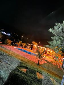 a pool at night with palm trees and lights at Pousada Chales da Canastra in Vargem Bonita