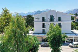 un bâtiment blanc avec des arbres devant lui dans l'établissement Perast City Hotel, à Antalya