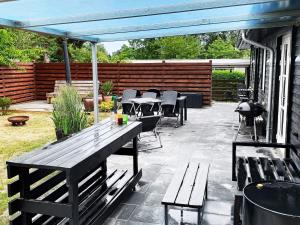 a patio with benches and tables and a blue canopy at 4 person holiday home in Gilleleje in Gilleleje