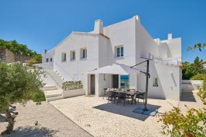 Casa blanca con mesa y sombrilla en Casa Do Levante3 Bedrooms With Sea View, en Vila Nova de Cacela