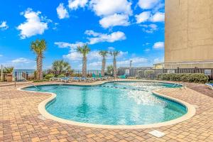 a swimming pool with palm trees and a building at The Palace 1702 in Myrtle Beach