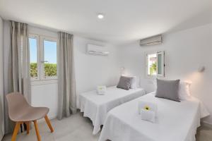 2 Betten in einem Zimmer mit weißen Wänden und Fenstern in der Unterkunft Casa Do Levante3 Bedrooms With Sea View in Vila Nova De Cacela