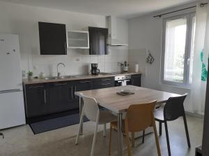 eine Küche mit einem Tisch und Stühlen sowie eine Küche mit einem Waschbecken in der Unterkunft Le gîte blinois in Blain