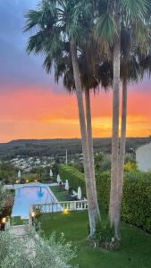 a pool with palm trees in front of a sunset at La Bastide in La Colle-sur-Loup