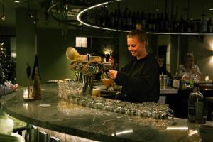 Una donna che prepara un drink al bar di Hotel Walram a Valkenburg
