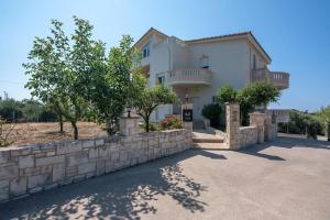 a large white house with a stone wall at Tonia's Residential Villa in Kissamos