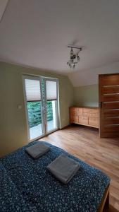 Schlafzimmer mit einem Bett, einer Kommode und Fenstern in der Unterkunft Domki Całoroczne Południowy Stok in Gmina Gródek nad Dunajcem