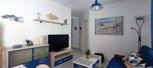 a living room with a blue couch and a tv at Mar Salada in L'Ametlla de Mar