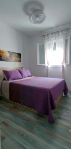fioletowe łóżko w sypialni z oknem w obiekcie Mar Salada w mieście L'Ametlla de Mar