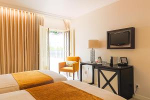 um quarto de hotel com duas camas e uma televisão em Josefa D`Obidos Hotel em Óbidos