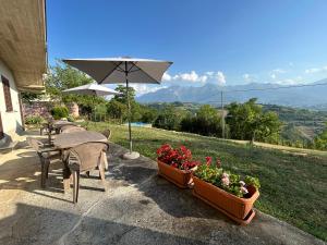 un tavolo con sedie e un ombrellone e alcuni fiori di Agriturismo Bellavista a Ronzano