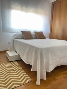 Schlafzimmer mit einem weißen Bett und einem Fenster in der Unterkunft Piso Sirius in Vilagarcia de Arousa