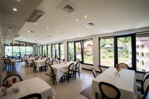 a restaurant with white tables and chairs and windows at Hotel Roman Maramures - Ski & Spa Resort in Statiunea Borsa