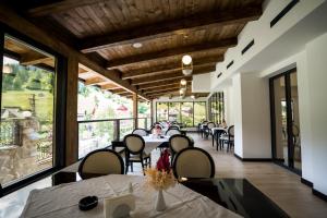 a restaurant with tables and chairs and large windows at Hotel Roman Maramures - Ski & Spa Resort in Statjunea Borsa