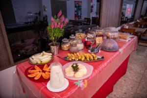 a red table with plates of food on it at Hotel Indiana in Paragominas