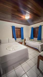 a bedroom with two beds and blue curtains at Village Miramar in Maragogi