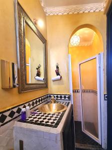 bagno con lavandino e specchio di Riad Jaime a Marrakech