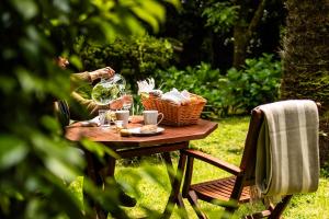 a woman sitting at a table with a basket of wine at Azores Green Villas in Ponta Delgada