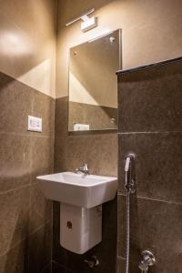 a bathroom with a sink and a mirror and a shower at MERIDIAN BY Daan in Trivandrum