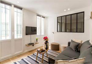 sala de estar con sofá y TV en Élégance & Design Paris Center, en París