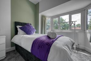 伯明罕的住宿－Team Accomodation 4 Bedroom Free Parking WiFi Moseley Birmingham near City Centre NEC BHX，一间卧室配有一张床铺,床上铺有紫色毯子