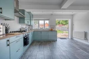 a kitchen with blue cabinets and a large window at Team Accomodation 4 Bedroom Free Parking WiFi Moseley Birmingham near City Centre NEC BHX in Birmingham