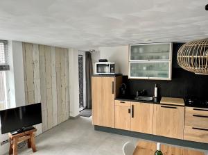 a kitchen with wooden cabinets and a tv in it at HuisjehurenEgmond in Egmond aan Zee
