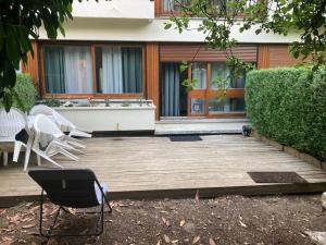 a wooden deck with chairs and a table in front of a house at Lovely studio 35 m2 with garden. 2/4 people in Le Chesnay