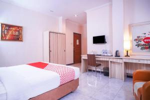 a bedroom with a bed and a desk and a television at Capital O 142 Hotel Al Furqon Syariah in Palembang