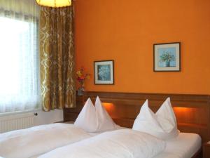 2 Betten in einem Hotelzimmer mit orangefarbenen Wänden in der Unterkunft Pension Brönimann in Ossiach