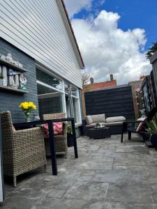 een patio met een tafel en stoelen en een bank bij HuisjehurenEgmond in Egmond aan Zee