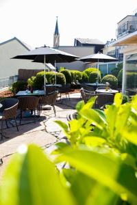 un patio con mesas, sillas y sombrillas en Villa Bosco - Digitales Boutiquehotel, en Walldorf