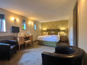 バンフォードにあるYorkshire Bridge Innのベッド、デスク、椅子が備わるホテルルームです。