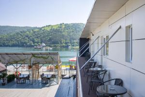 a balcony with tables and chairs and a view of a lake at Hotel Plutitor Lebăda in Bicaz