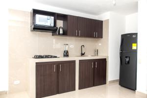 uma cozinha com armários castanhos e um frigorífico preto em Apartamento con vistas en Cali 