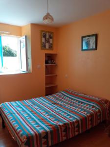 ein Schlafzimmer mit einem Bett mit einer bunten Decke in der Unterkunft LE PETIT PLESSIS CURE in Liré