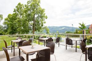 eine Terrasse in einem Restaurant mit Tischen und Stühlen in der Unterkunft JUFA Hotel Stubenbergsee in Stubenberg