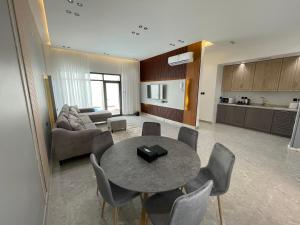 ein Wohnzimmer mit einem Tisch und Stühlen sowie eine Küche in der Unterkunft أعناب الفندقية in Baljurashi