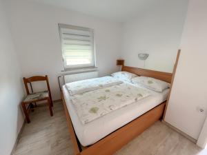 a small bedroom with a bed and a chair at Apartments Sole in Podčetrtek