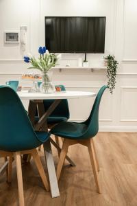 einem Esstisch mit 2 grünen Stühlen und einem TV in der Unterkunft AGF Luxury Apartment in Catania