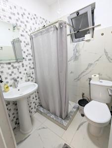 a white bathroom with a toilet and a sink at GuestHouse Panorama Nivice in Sarandë +29 photos
