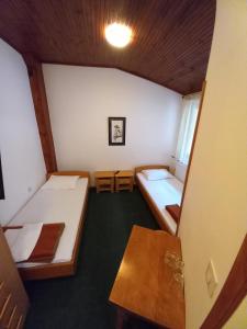 Habitación pequeña con 2 camas y mesa. en Dom Plus, en Ovčar Banja