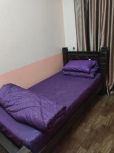 a bed with purple sheets and pillows in a room at Siti Homestay in Pasir Mas