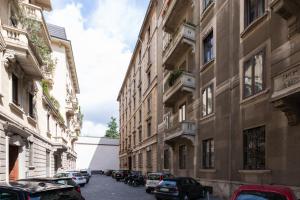 een stadsstraat met geparkeerde auto's en gebouwen bij Moscova Cosy Apartment in Milaan