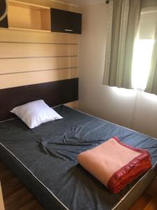 1 dormitorio con cama con almohada y ventana en Mobil home en Damiatte
