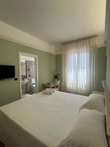 a bedroom with a large white bed and a bathroom at Hotel Aquila in Castelfranco Emilia
