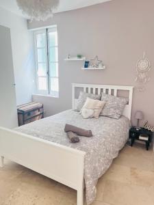 een witte slaapkamer met een wit bed met twee schoenen erop bij La Belle de l’Isle in LʼIsle-sur-la-Sorgue