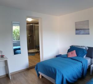a bedroom with a blue bed and a mirror at Détente champêtre, maisonnette rénovée en 2023 